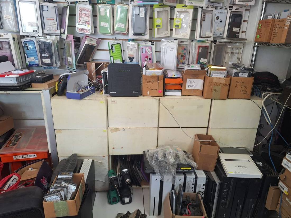 Banco de trabajo con laptops, MacBook y consolas en reparación
